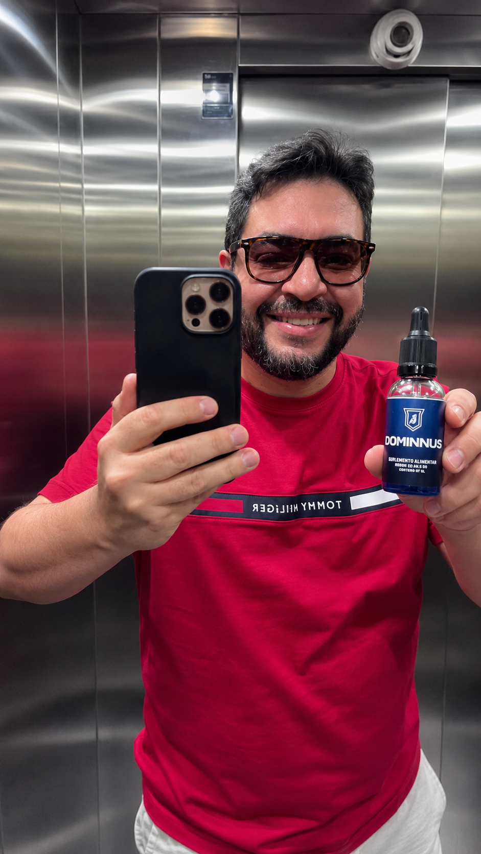 Homem sorrindo em selfie no espelho segurando o frasco de Dominnus